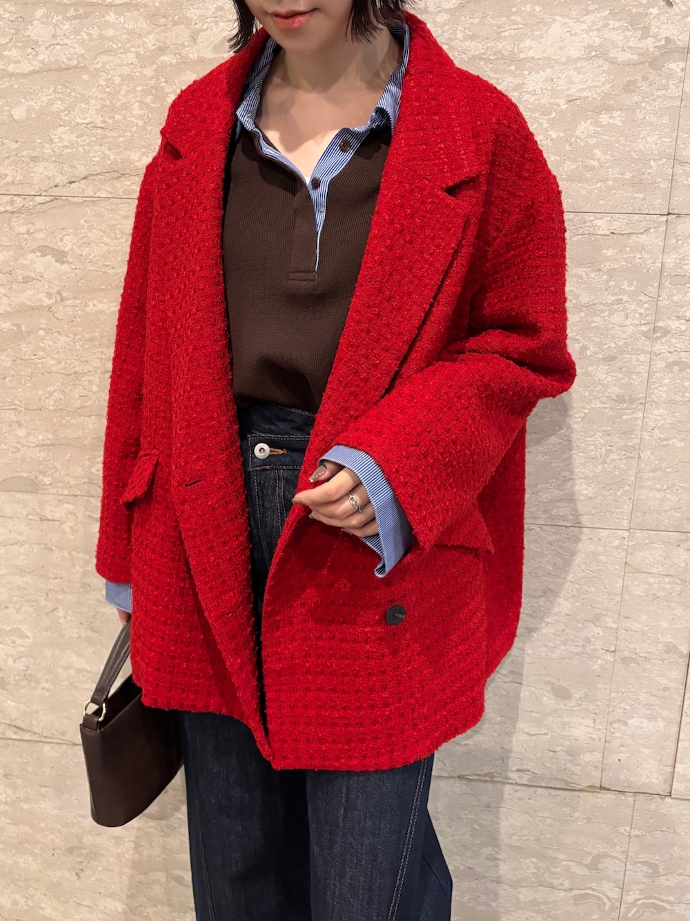 ブルー系のデニムパンツ、ブラウン系のニット/セーター、ブラウン系のハンドバッグを着用したレディースの冬コーディネートの6枚目の写真