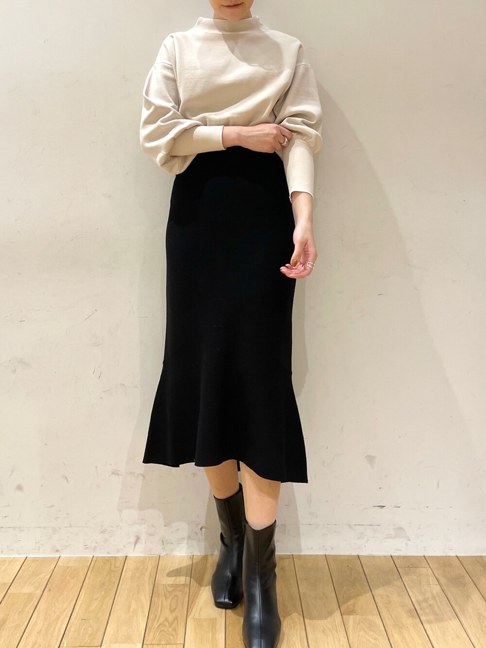 ブラック系のスカート、ホワイト系のニット/セーター、ブラック系のブーツを着用したレディースの冬コーディネートの7枚目の写真