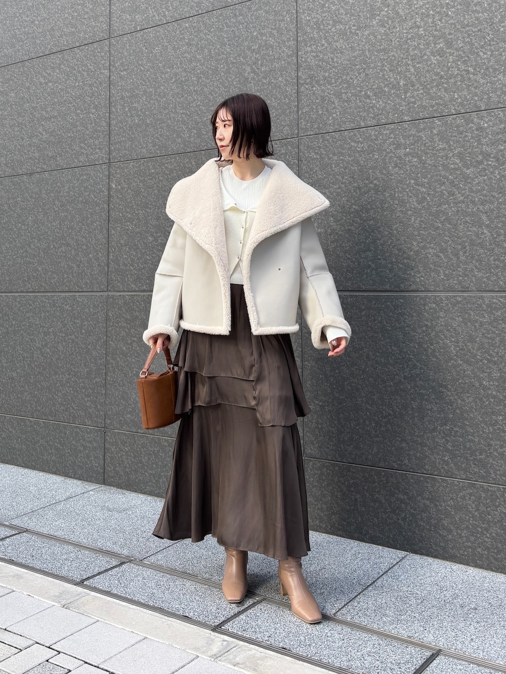 ブラウン系のスカート、イエロー系のハンドバッグ、ベージュ系のブーツを着用したレディースの冬コーディネートの6枚目の写真