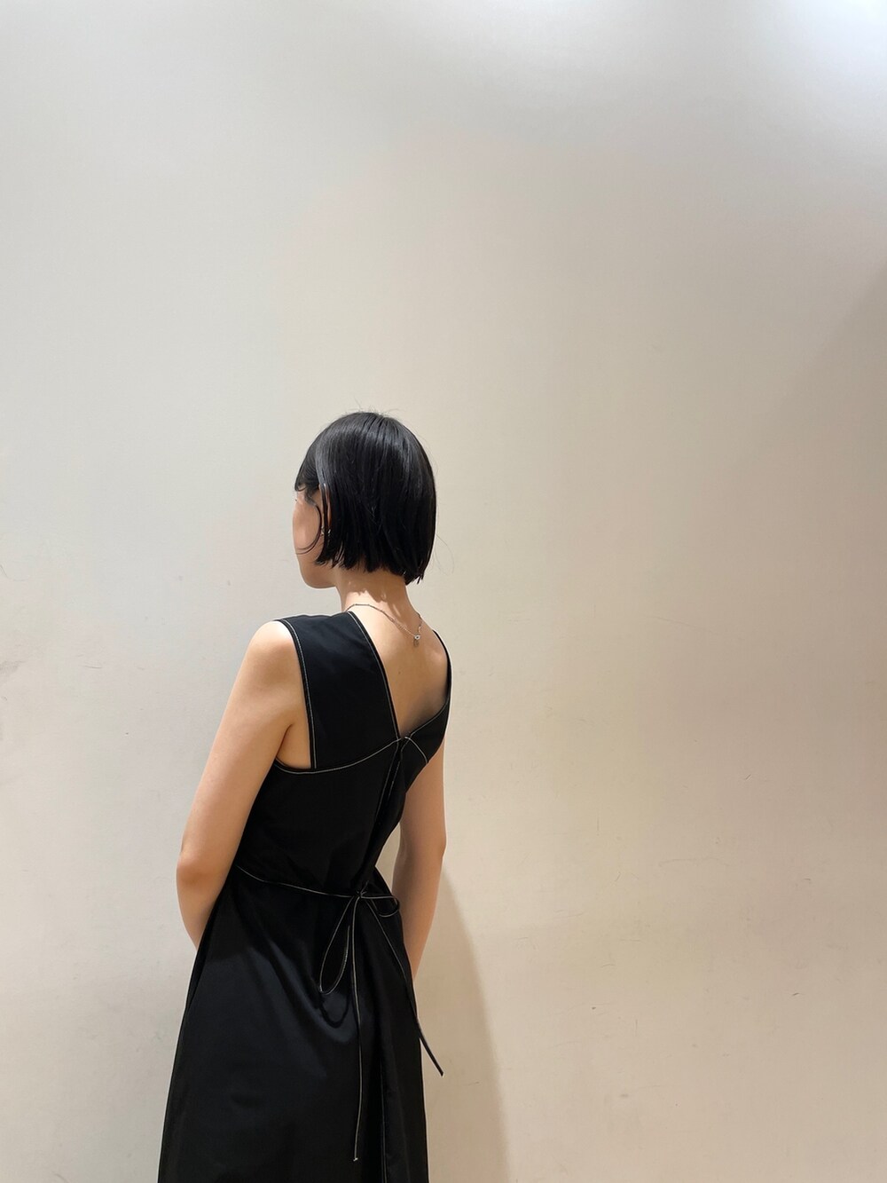 ブラック系のワンピース、ホワイト系のハンドバッグ、ホワイト系のネックレスを着用したレディースの夏コーディネートの9枚目の写真