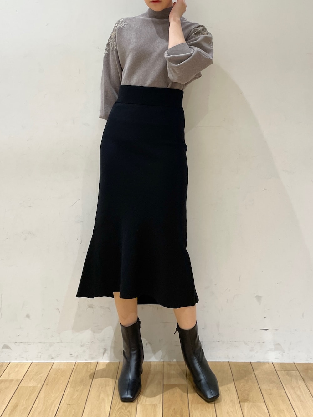 ブラック系のスカート、グレー系のニット/セーター、ブラック系のブーツを着用したレディースの冬コーディネートの3枚目の写真