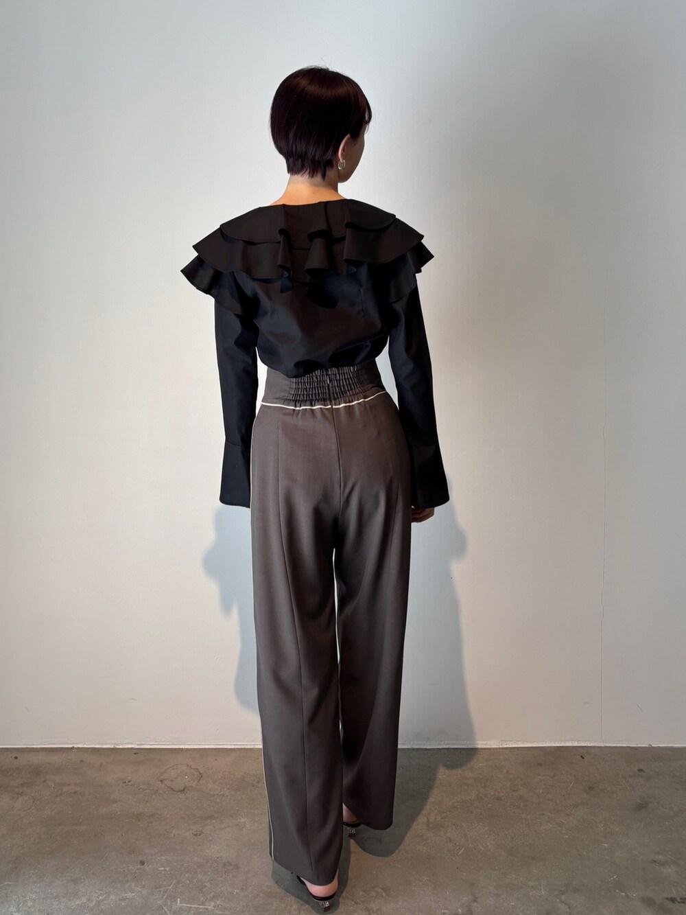 グレー系のスラックス、ブラック系のシャツ/ブラウス、ブラック系のサンダルを着用したレディースの春コーディネートの3枚目の写真