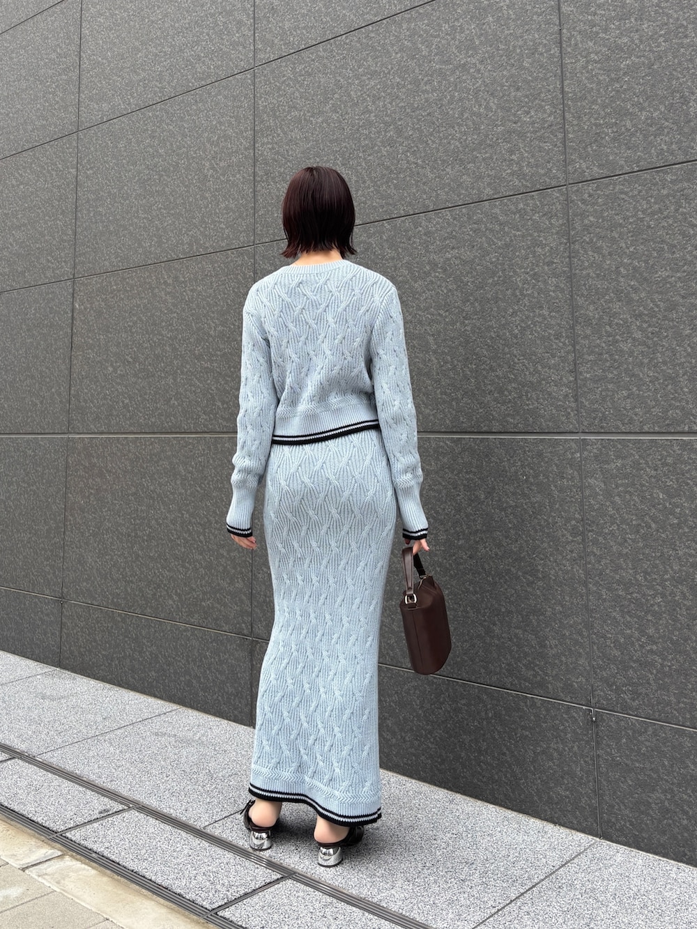 ブルー系のワンピース、ブラウン系のハンドバッグ、ブラウン系のパンプスを着用したレディースの冬コーディネートの4枚目の写真