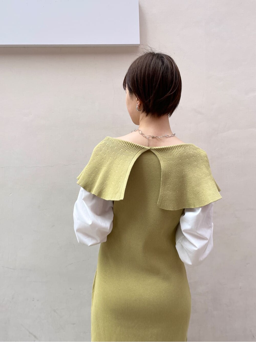 ベージュ系のハンドバッグ、ベージュ系のトレンチコート、イエロー系のワンピースを着用したレディースの冬コーディネートの5枚目の写真