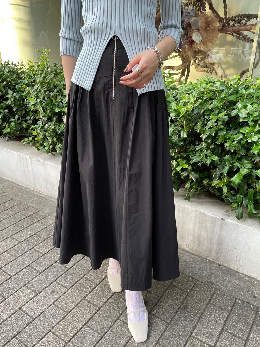 ブラック系のスカート、ブルー系のニット/セーター、ホワイト系のパンプスを着用したレディースの春コーディネートの5枚目の写真