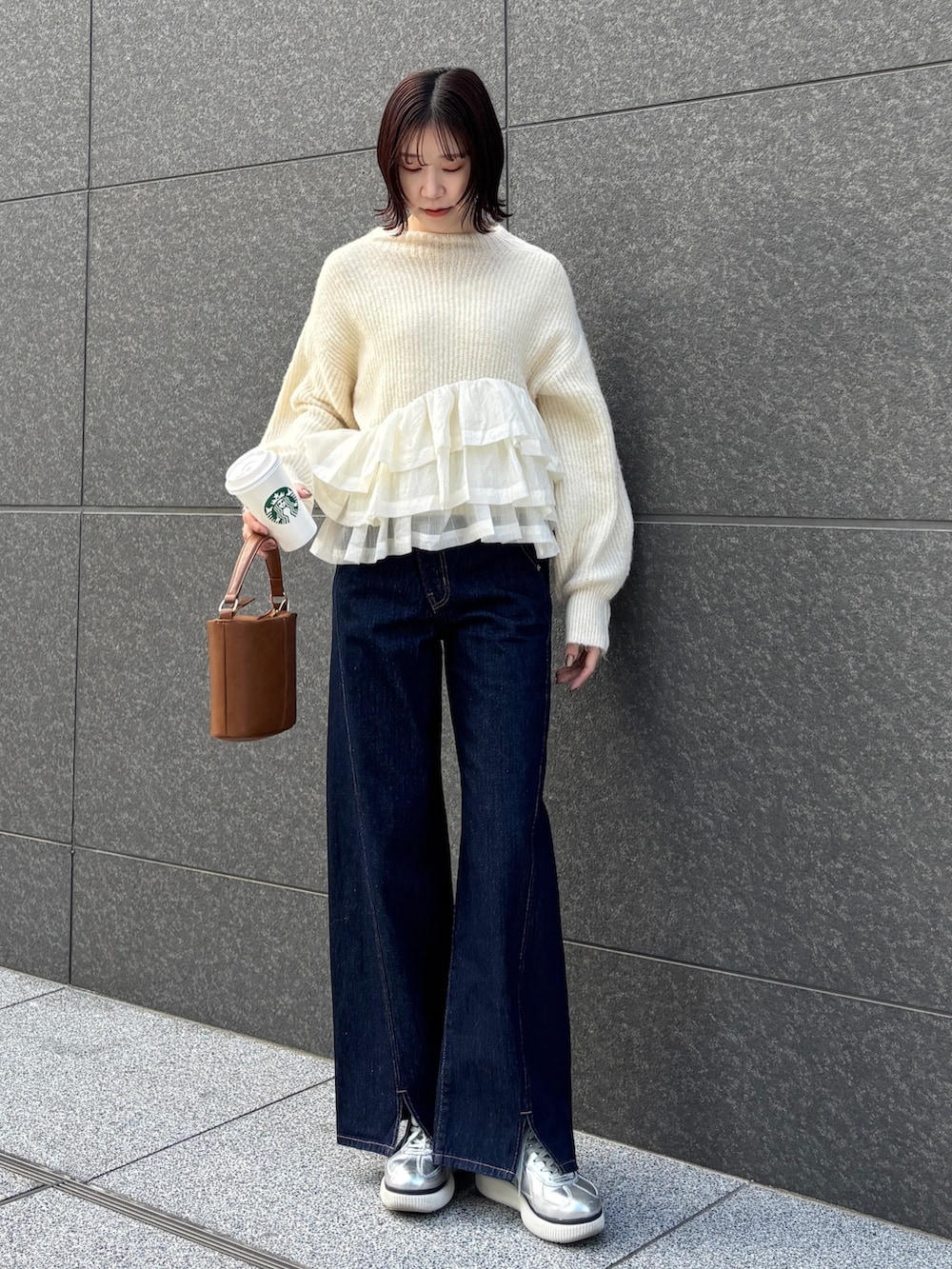 ブルー系のデニムパンツ、イエロー系のハンドバッグ、ホワイト系のニット/セーターを着用したレディースの冬コーディネートの2枚目の写真