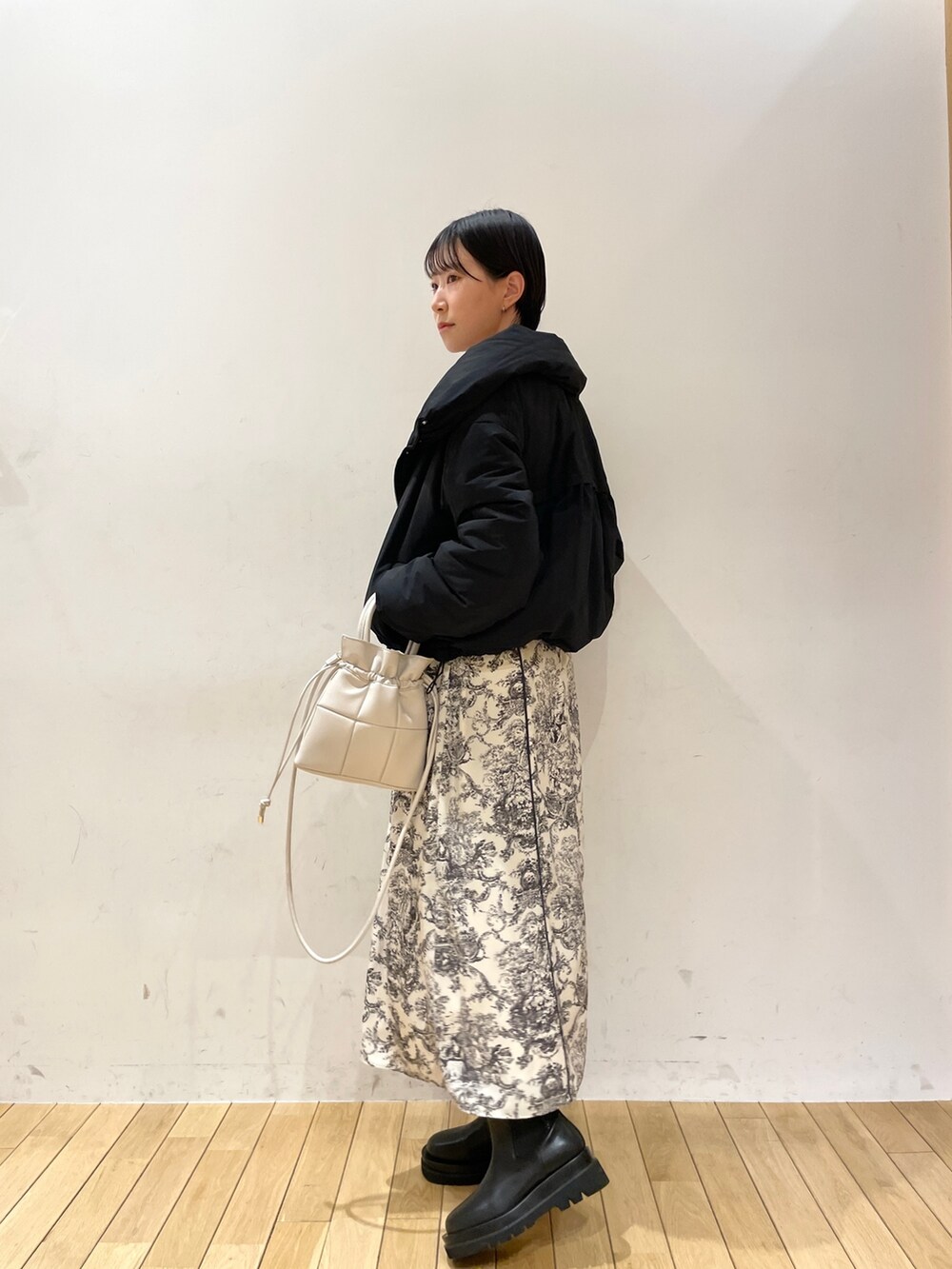 ブラック系のダウンジャケット/コート、ホワイト系のワンピース、ブラック系のブーツを着用したレディースの冬コーディネートの5枚目の写真