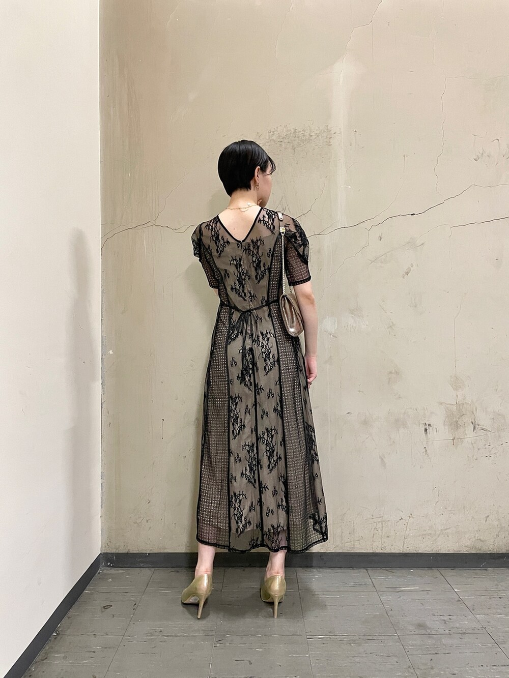 ブラック系のドレス、ゴールド系のハンドバッグ、ゴールド系のパンプスを着用したレディースの秋コーディネートの4枚目の写真