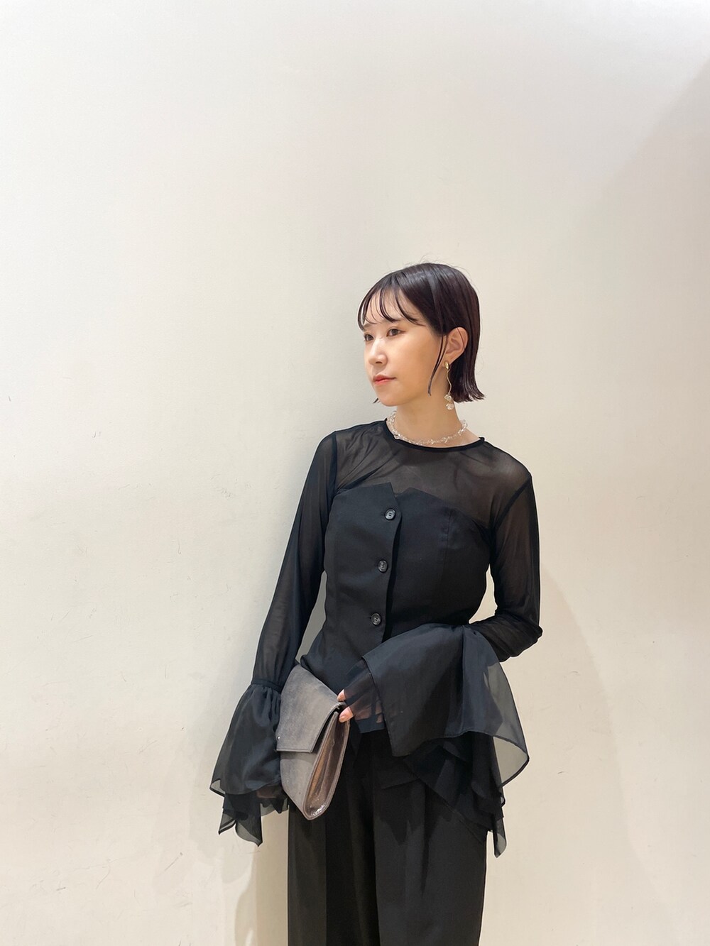 シルバー系のハンドバッグ、シルバー系のパンプス、ブラック系のパンツドレスを着用したレディースの秋コーディネートの7枚目の写真