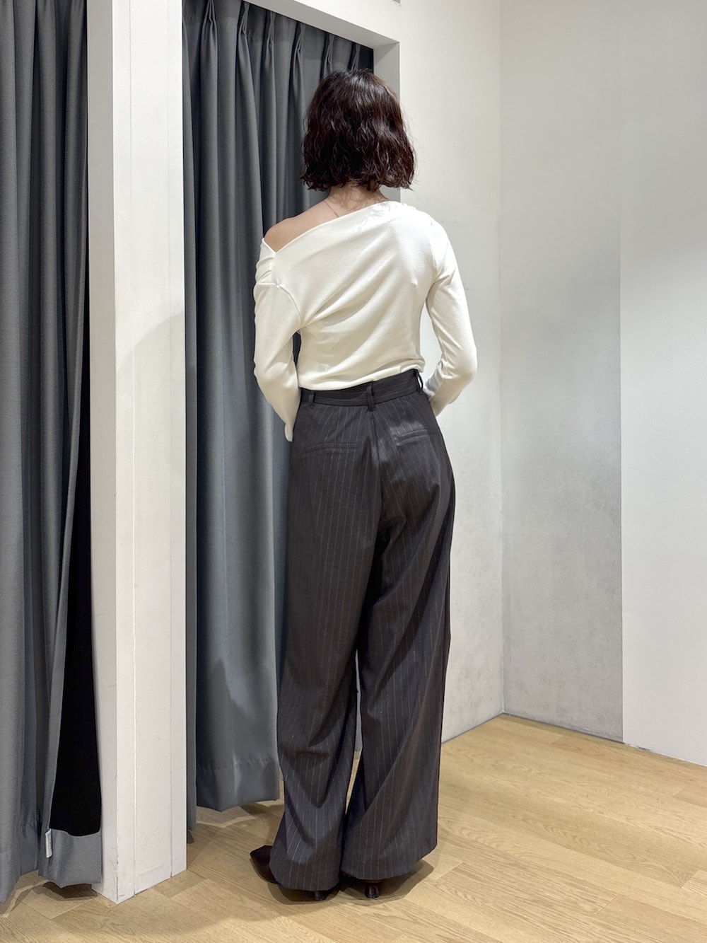 グレー系のその他パンツ、ホワイト系のニット/セーター、レッド系のハンドバッグを着用したレディースの秋コーディネートの3枚目の写真