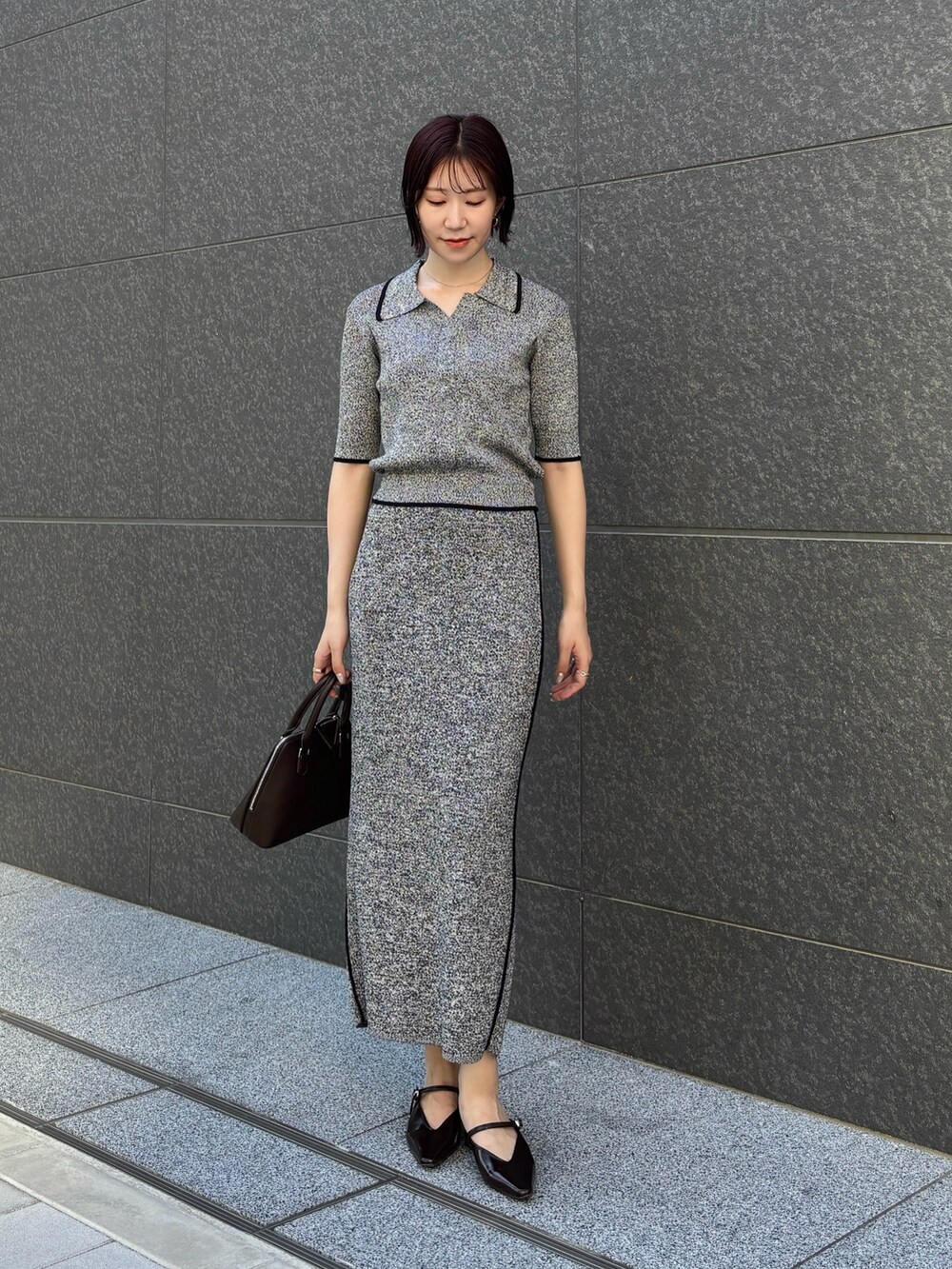 ブラック系のワンピース、ブラウン系のボストンバッグ、ブラウン系のパンプスを着用したレディースの夏コーディネートの2枚目の写真