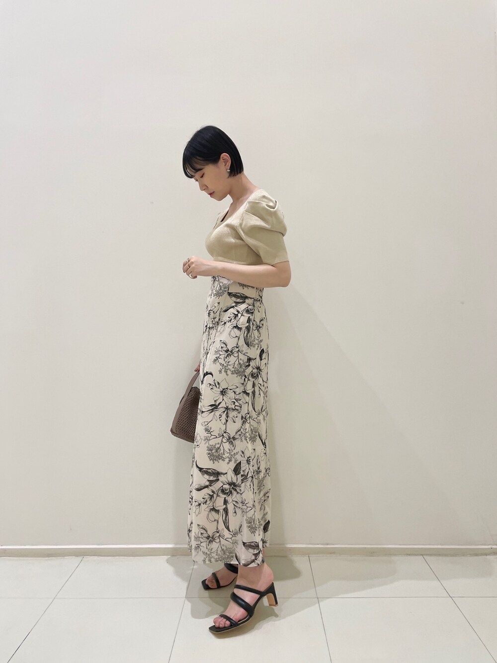 ホワイト系のスカート、ベージュ系のニット/セーター、ブラウン系のハンドバッグを着用したレディースの春コーディネートの3枚目の写真