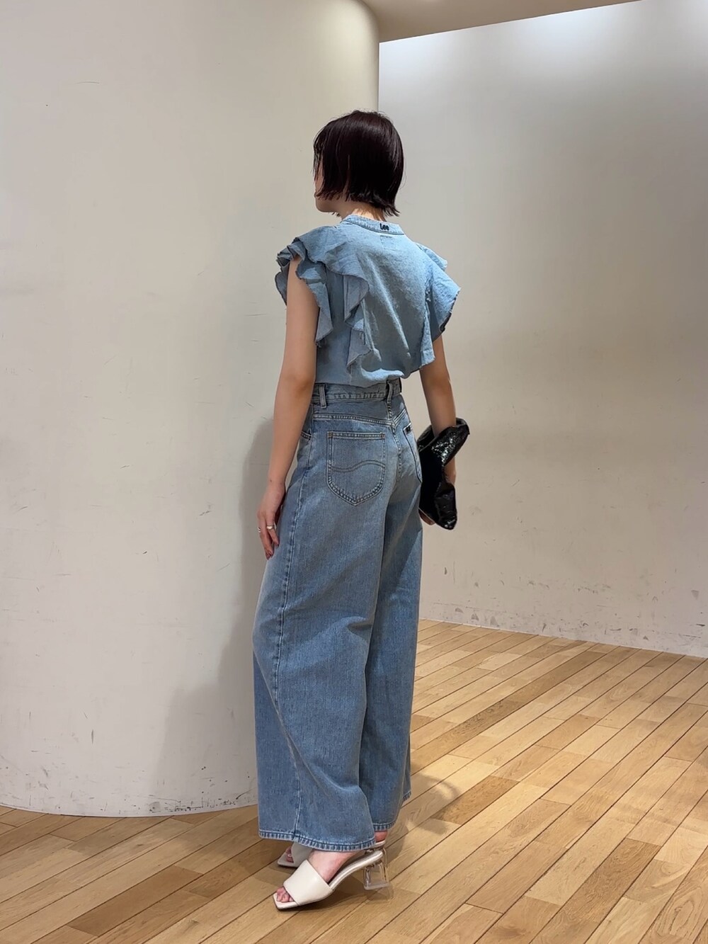 ブルー系のデニムパンツ、ブルー系のシャツ/ブラウス、ホワイト系のサンダルを着用したレディースの夏コーディネートの2枚目の写真