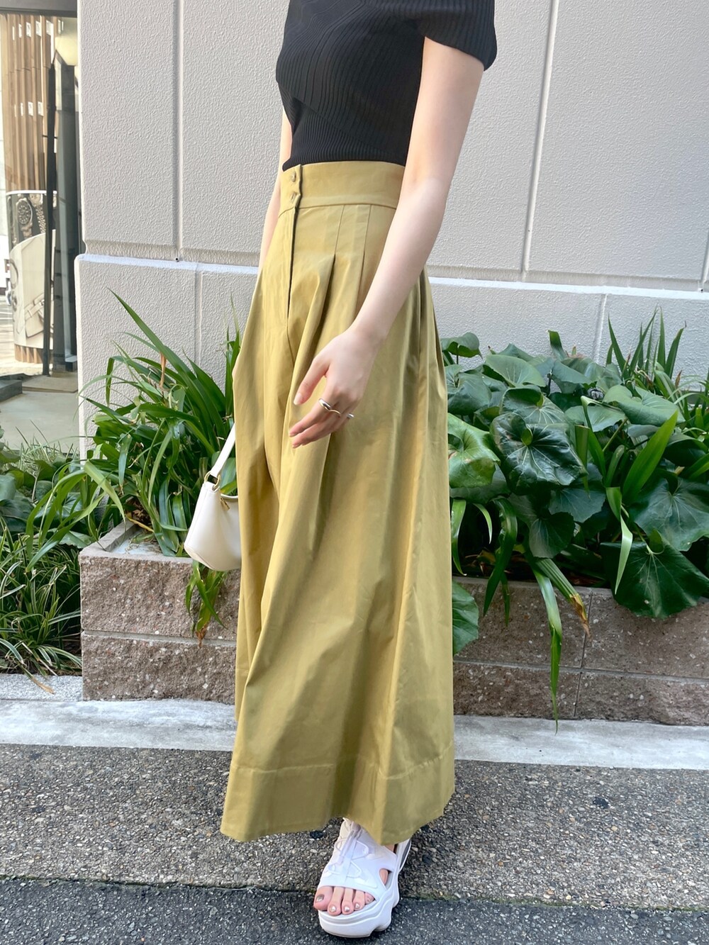 ブラック系のニット/セーター、イエロー系のスカート、ホワイト系のハンドバッグを着用したレディースの夏コーディネートの7枚目の写真