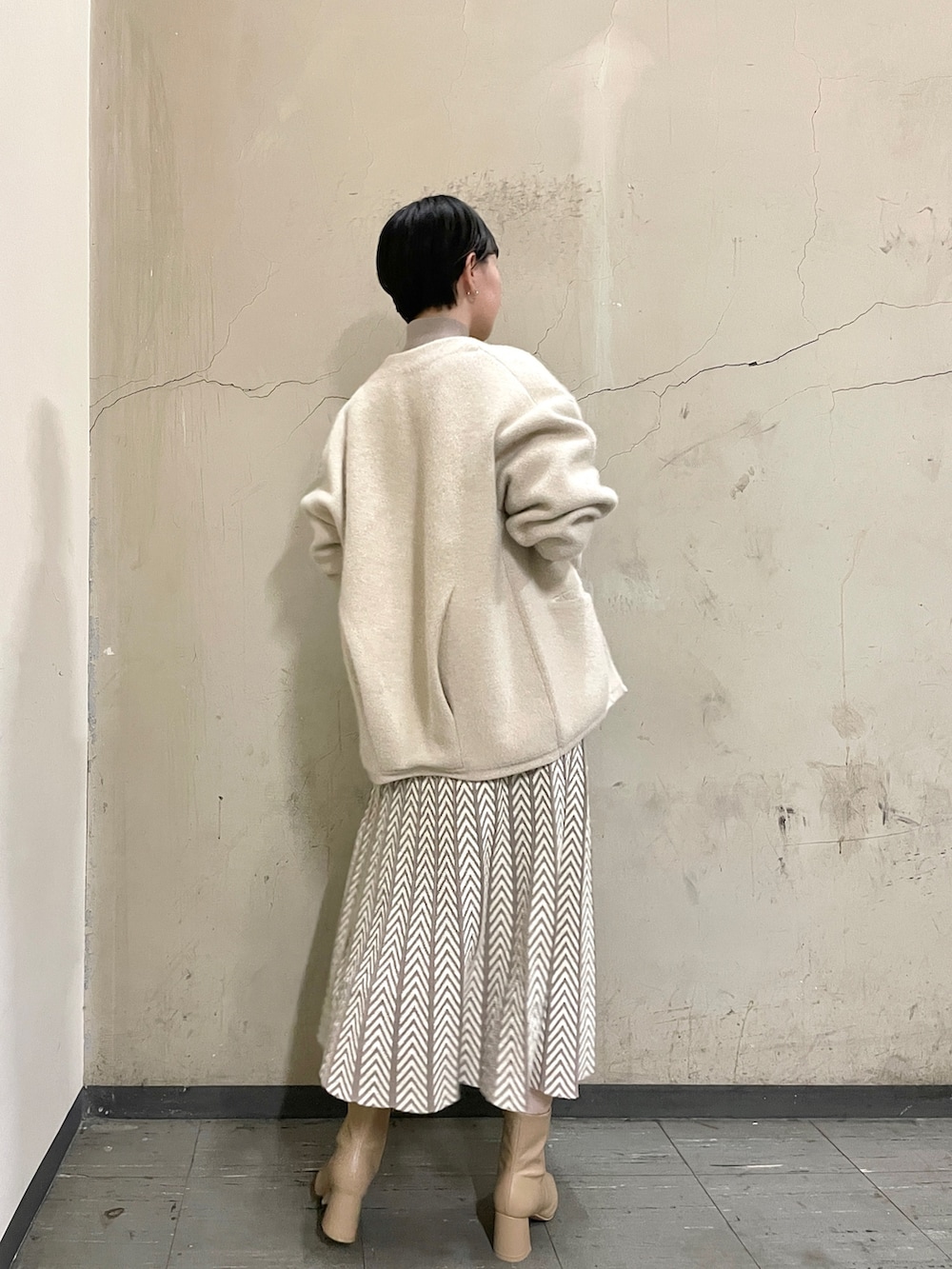 ホワイト系のカーディガン/ボレロ、ベージュ系のブーツ、ホワイト系のハンドバッグを着用したレディースの冬コーディネートの5枚目の写真