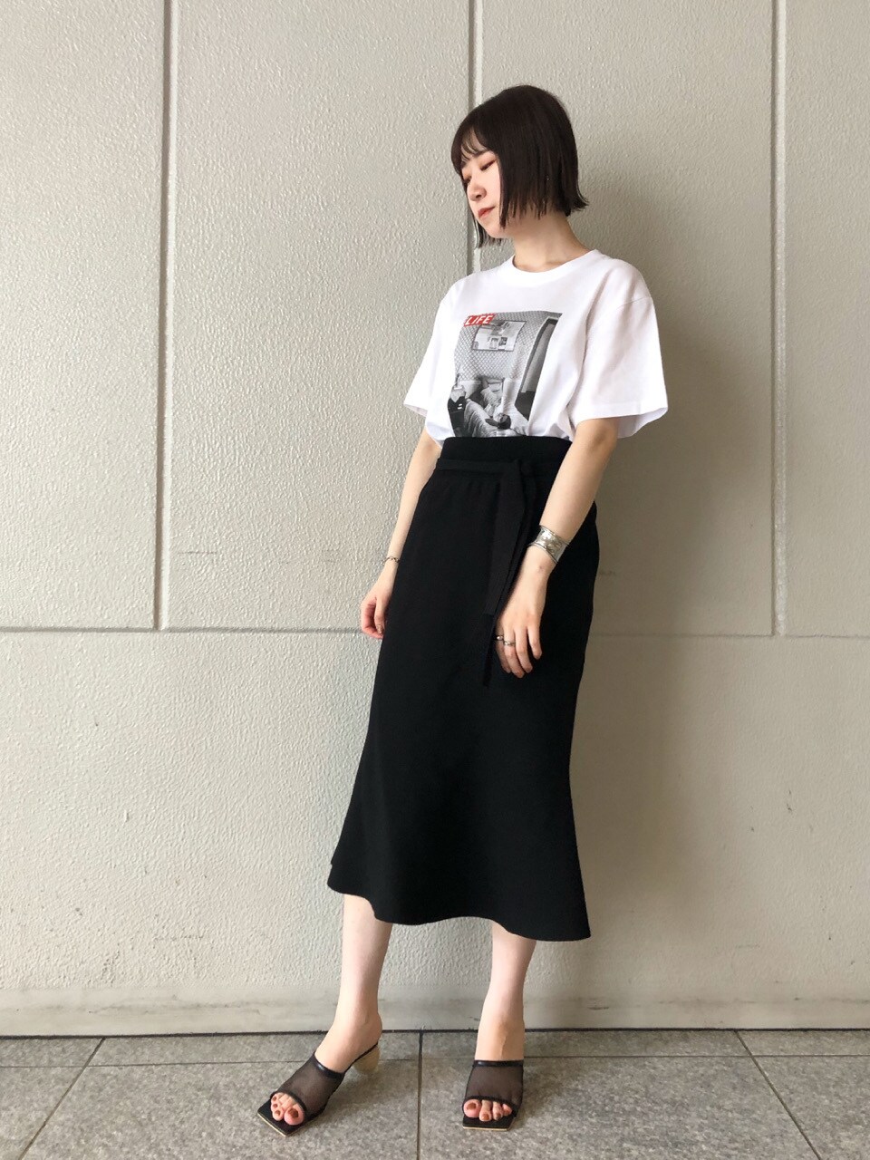 ブラック系のスカート、ブラック系のその他シューズ、ホワイト系のTシャツ/カットソーを着用したレディースの夏コーディネートの3枚目の写真