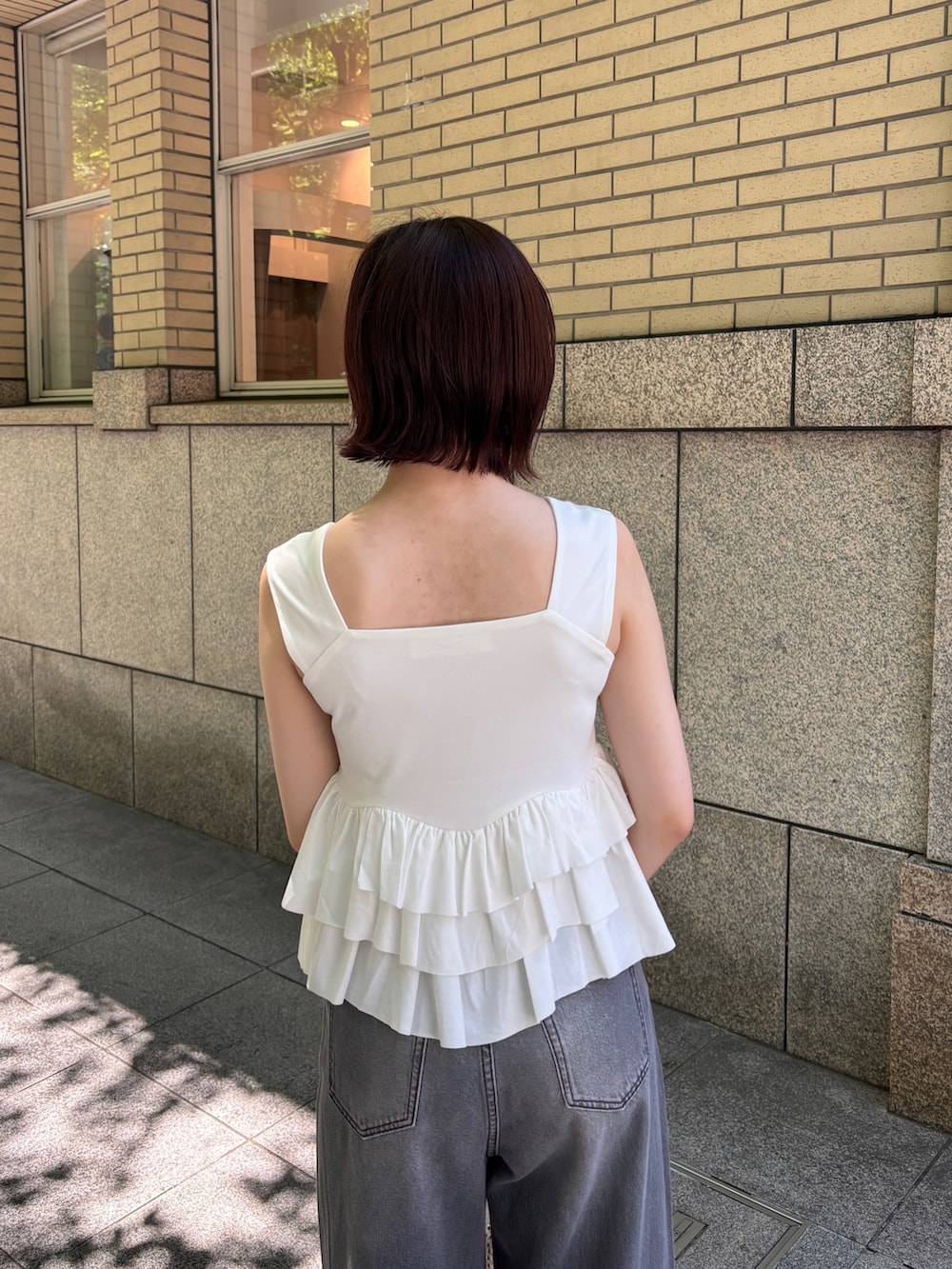 グレー系のデニムパンツ、ホワイト系のハンドバッグ、ホワイト系のサンダルを着用したレディースの春コーディネートの6枚目の写真