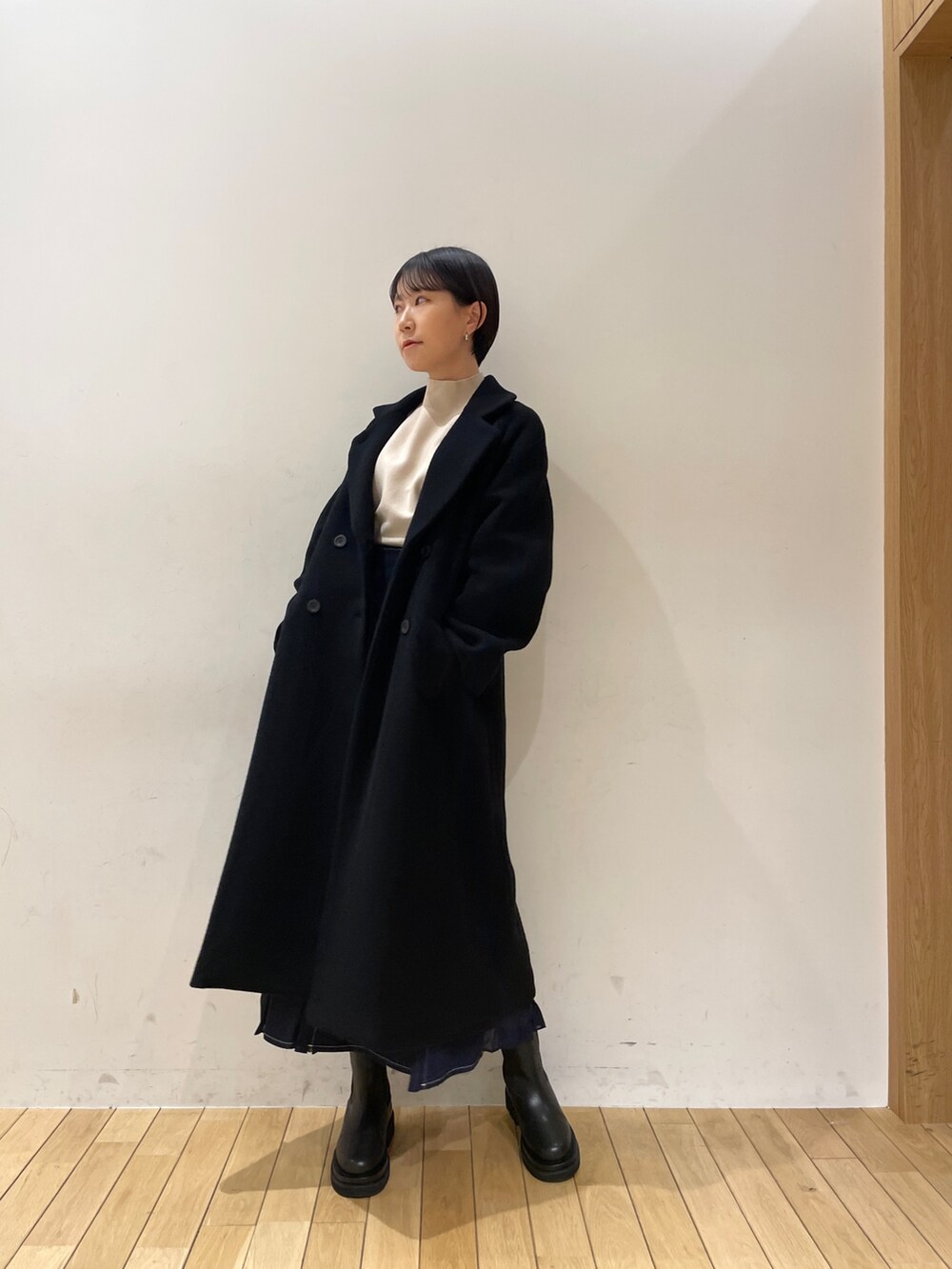 ブラック系のその他アウター、ホワイト系のニット/セーター、ブルー系のスカートを着用したレディースの冬コーディネートの4枚目の写真