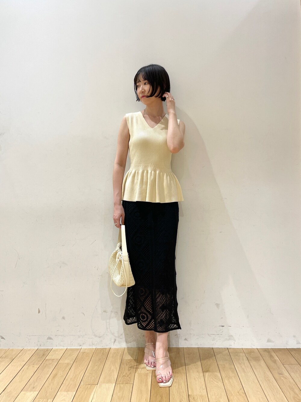 ベージュ系のハンドバッグ、ホワイト系のニット/セーター、ブラック系のスカートを着用したレディースの夏コーディネートの2枚目の写真