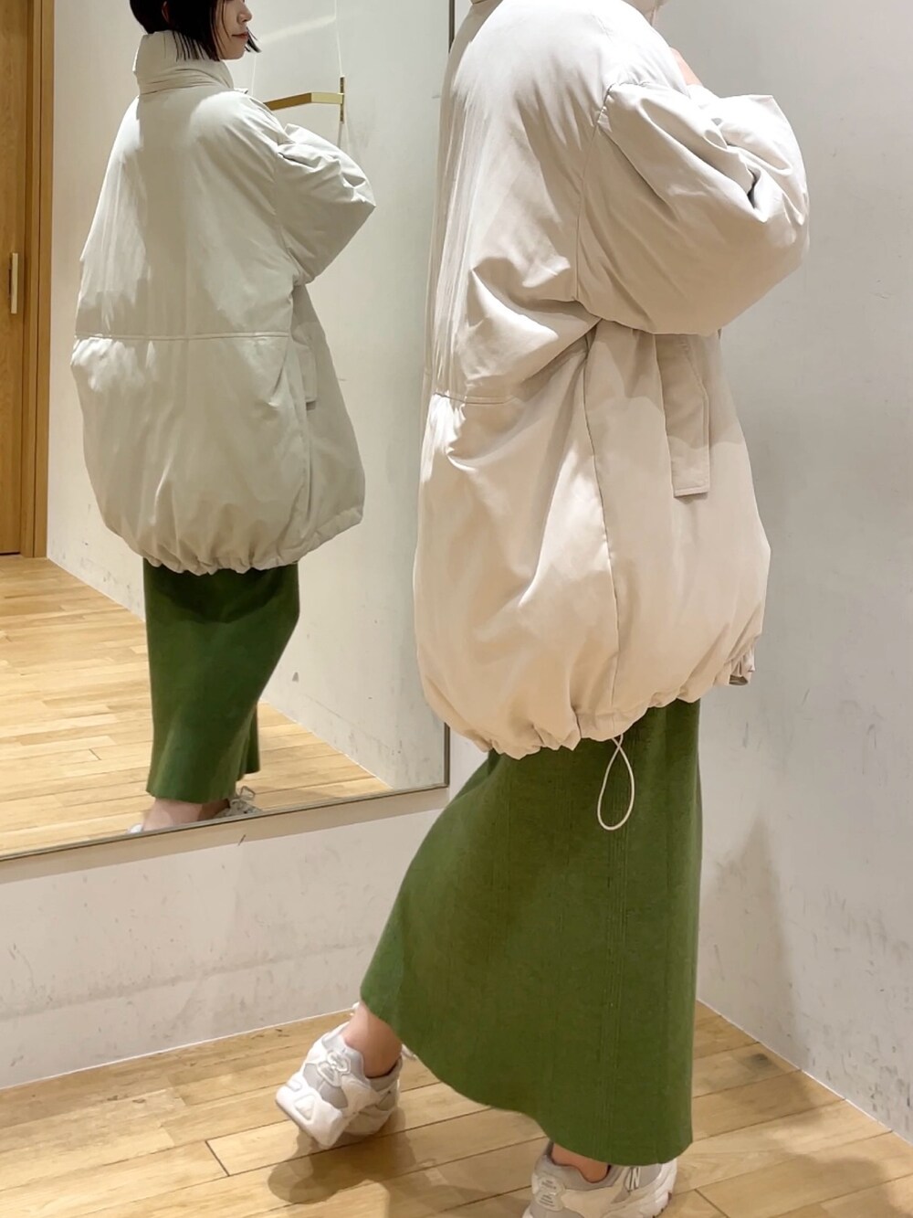 グリーン系のワンピース、ホワイト系のダウンジャケット/コート、ブラック系のチェスターコートを着用したレディースの冬コーディネートの3枚目の写真