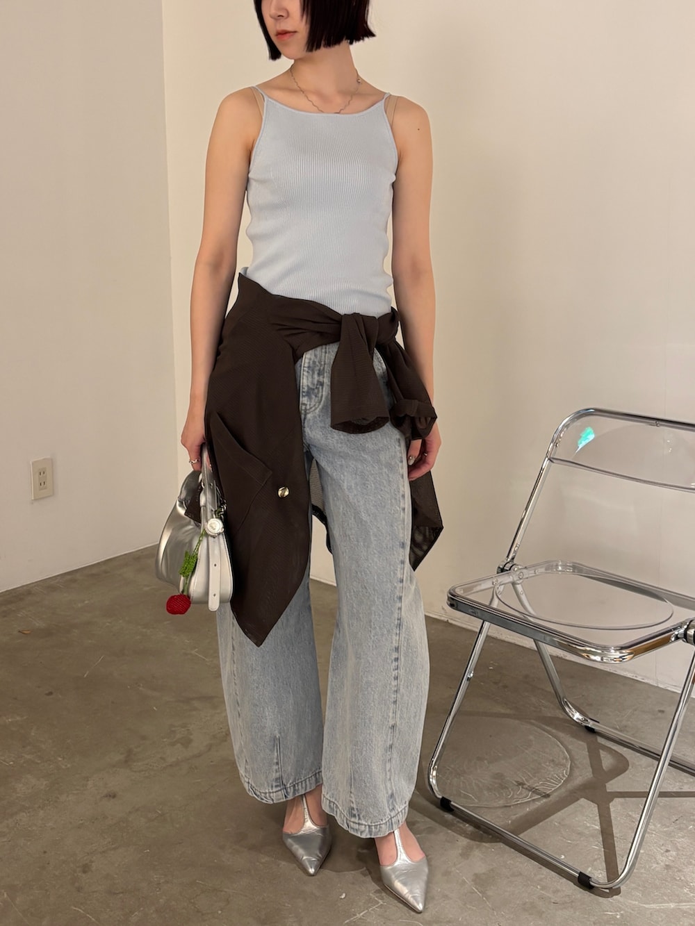 ブルー系のデニムパンツ、ブラウン系のテーラードジャケット、ブルー系のタンクトップを着用したレディースの春コーディネートの6枚目の写真