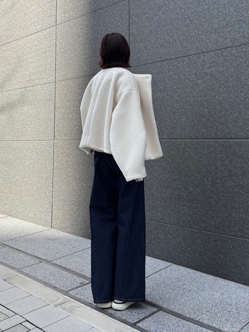 ホワイト系のブルゾン、ブルー系のデニムパンツ、イエロー系のハンドバッグを着用したレディースの冬コーディネートの4枚目の写真