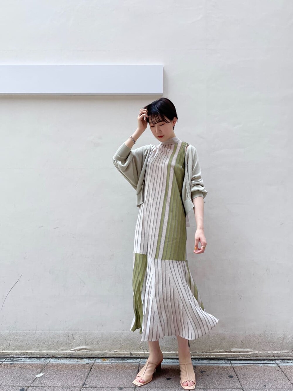 グリーン系のワンピース、グリーン系のカーディガン/ボレロ、ベージュ系のサンダルを着用したレディースの夏コーディネートの4枚目の写真