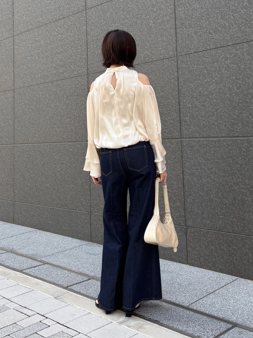 ホワイト系のシャツ/ブラウス、ホワイト系のハンドバッグ、ベージュ系のテーラードジャケットを着用したレディースの春コーディネートの6枚目の写真