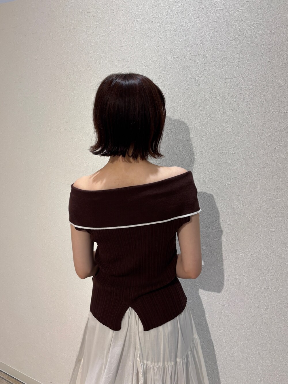 ホワイト系のスカート、ブラウン系のニット/セーター、ブラック系のハンドバッグを着用したレディースの夏コーディネートの6枚目の写真