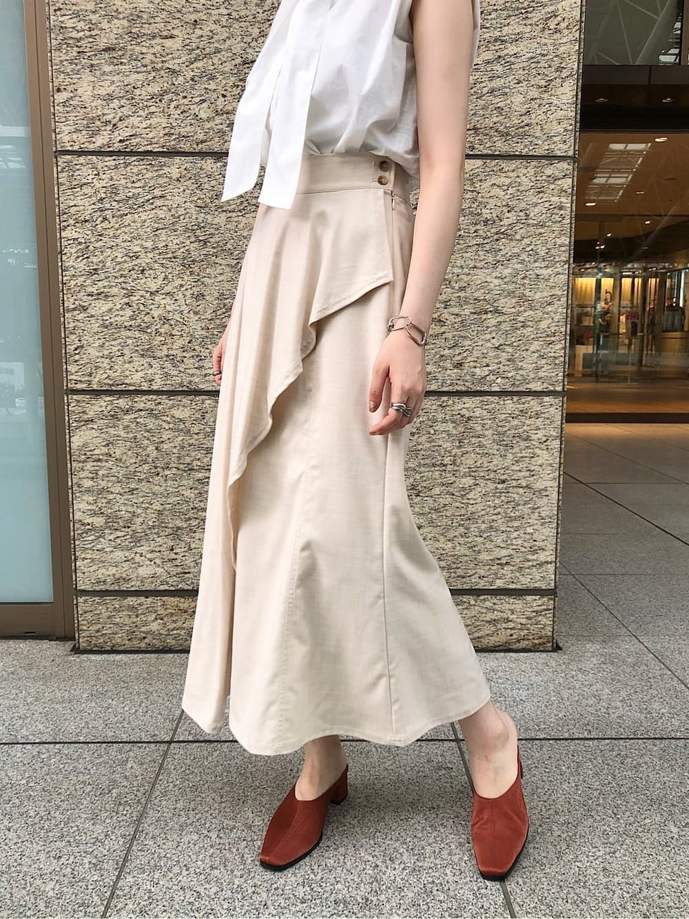 ホワイト系のシャツ/ブラウス、ホワイト系のスカート、オレンジ系のスリッポンを着用したレディースの夏コーディネートの3枚目の写真