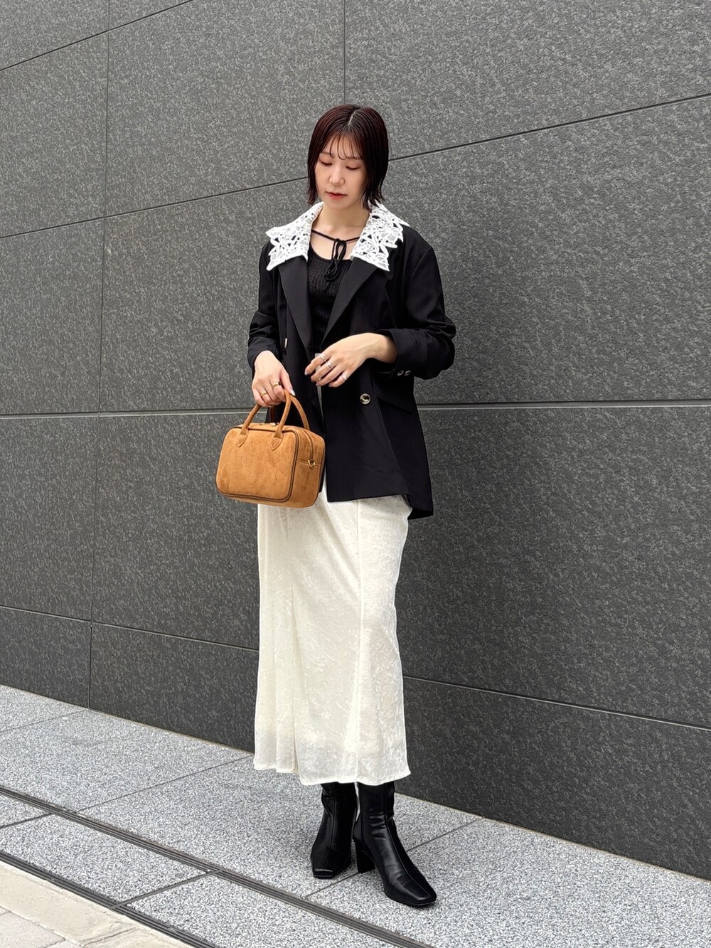 ホワイト系のスカート、イエロー系のハンドバッグ、ブラック系のブーツを着用したレディースの秋コーディネートの3枚目の写真