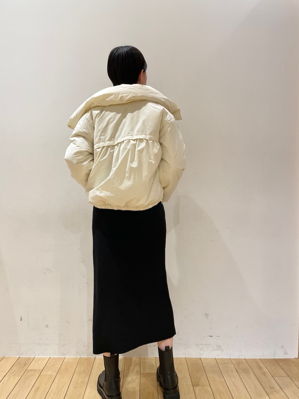 ブラック系のワンピース、ホワイト系のハンドバッグ、ブラック系のブーツを着用したレディースの冬コーディネートの7枚目の写真