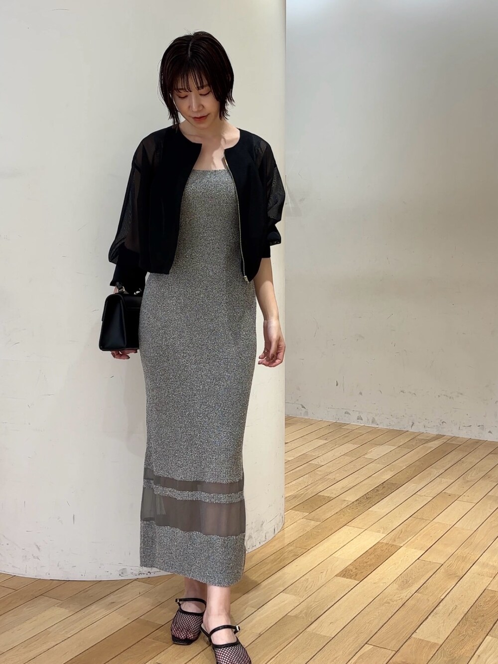 グレー系のワンピース、ブラック系のブルゾン、ブラック系のハンドバッグを着用したレディースの春コーディネートの2枚目の写真