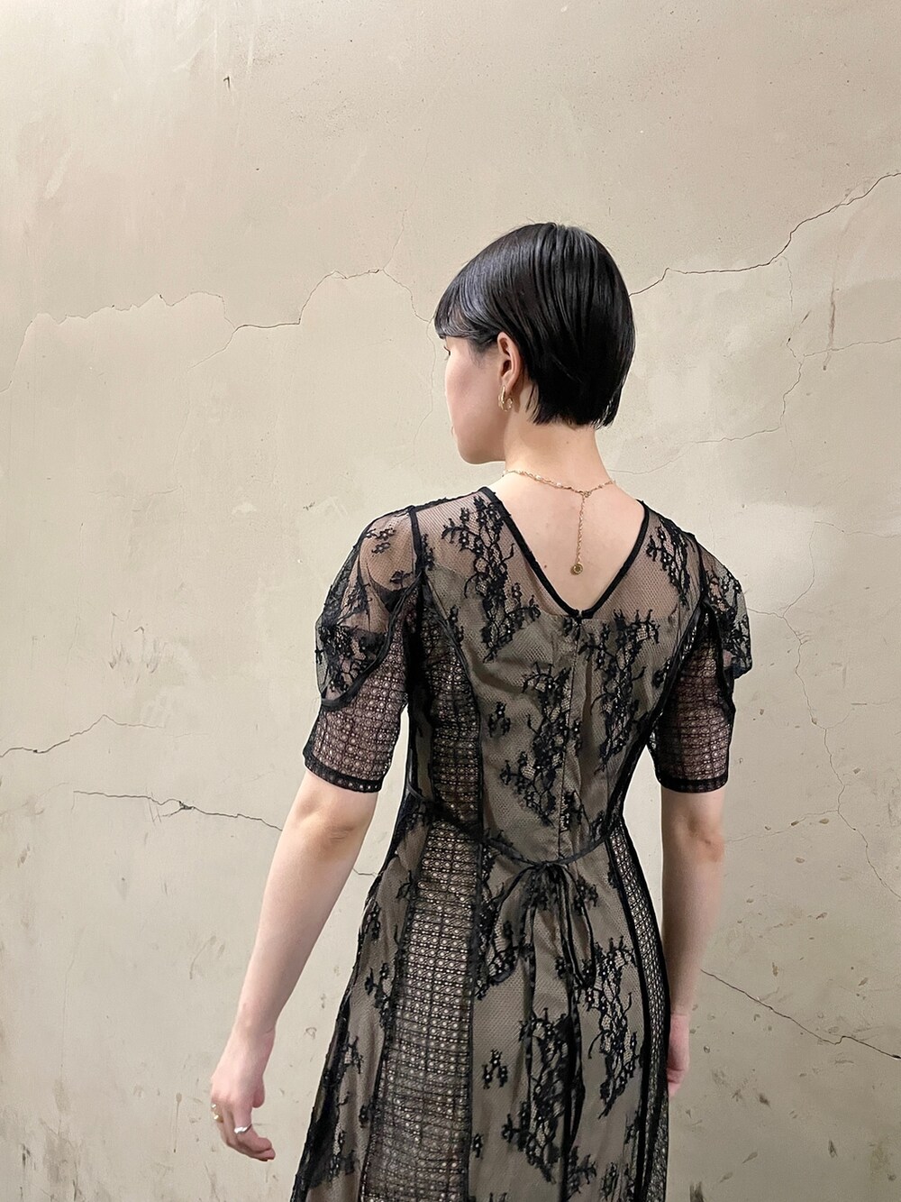 ブラック系のドレス、ゴールド系のハンドバッグ、ゴールド系のパンプスを着用したレディースの秋コーディネートの6枚目の写真