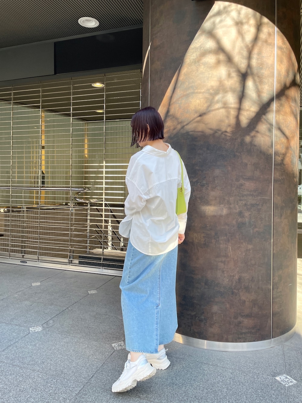 ホワイト系のシャツ/ブラウス、グリーン系のデニムスカート、ホワイト系のスニーカーを着用したレディースの春コーディネートの3枚目の写真