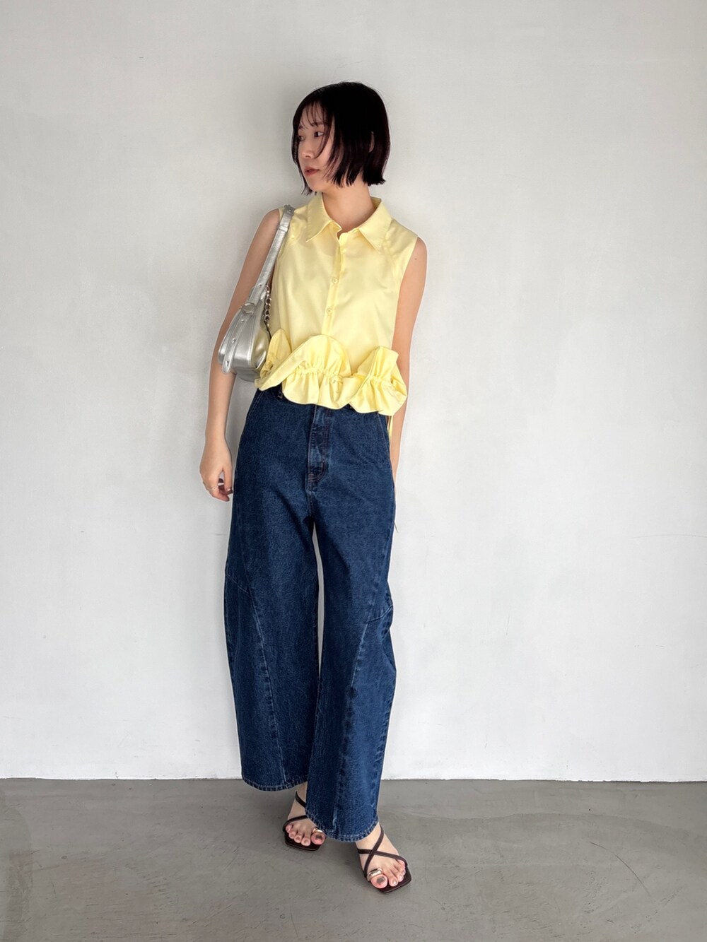 ブルー系のデニムパンツ、イエロー系のシャツ/ブラウス、シルバー系のハンドバッグを着用したレディースの夏コーディネートの2枚目の写真
