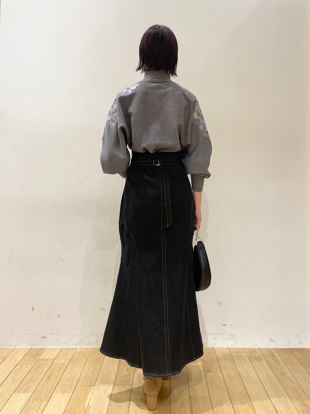 ベージュ系のブーツ、ブラック系のデニムスカート、ブラック系のハンドバッグを着用したレディースの夏コーディネートの5枚目の写真