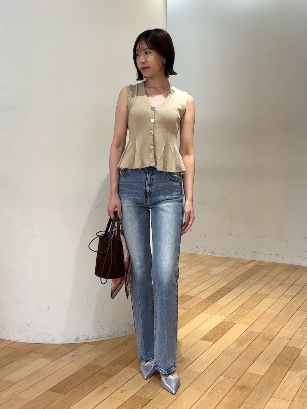 ブルー系のデニムパンツ、ブラウン系のハンドバッグ、シルバー系のパンプスを着用したレディースの夏コーディネートの2枚目の写真