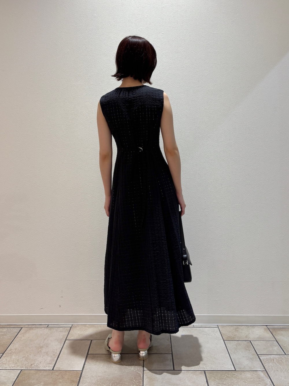 ブラック系のワンピース、ブラック系のハンドバッグ、グリーン系のパンプスを着用したレディースの夏コーディネートの4枚目の写真