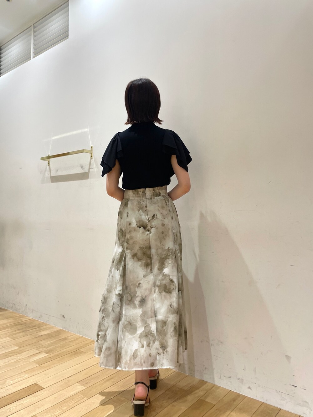 ブラック系のサンダル、グレー系のスカート、ブラック系のニット/セーターを着用したレディースの夏コーディネートの4枚目の写真