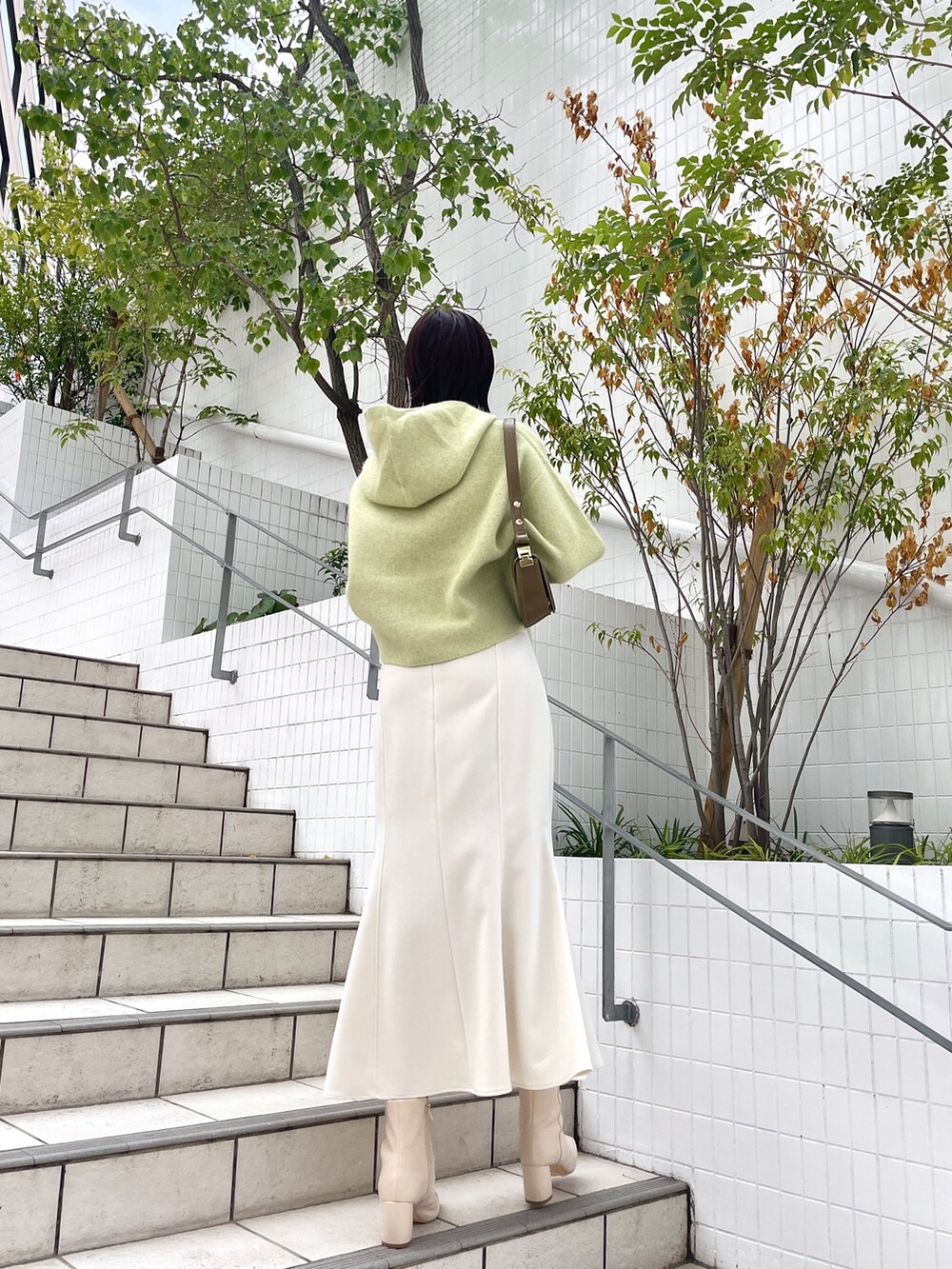 ホワイト系のスカート、グリーン系のパーカー、ホワイト系のブーツを着用したレディースの秋コーディネートの4枚目の写真