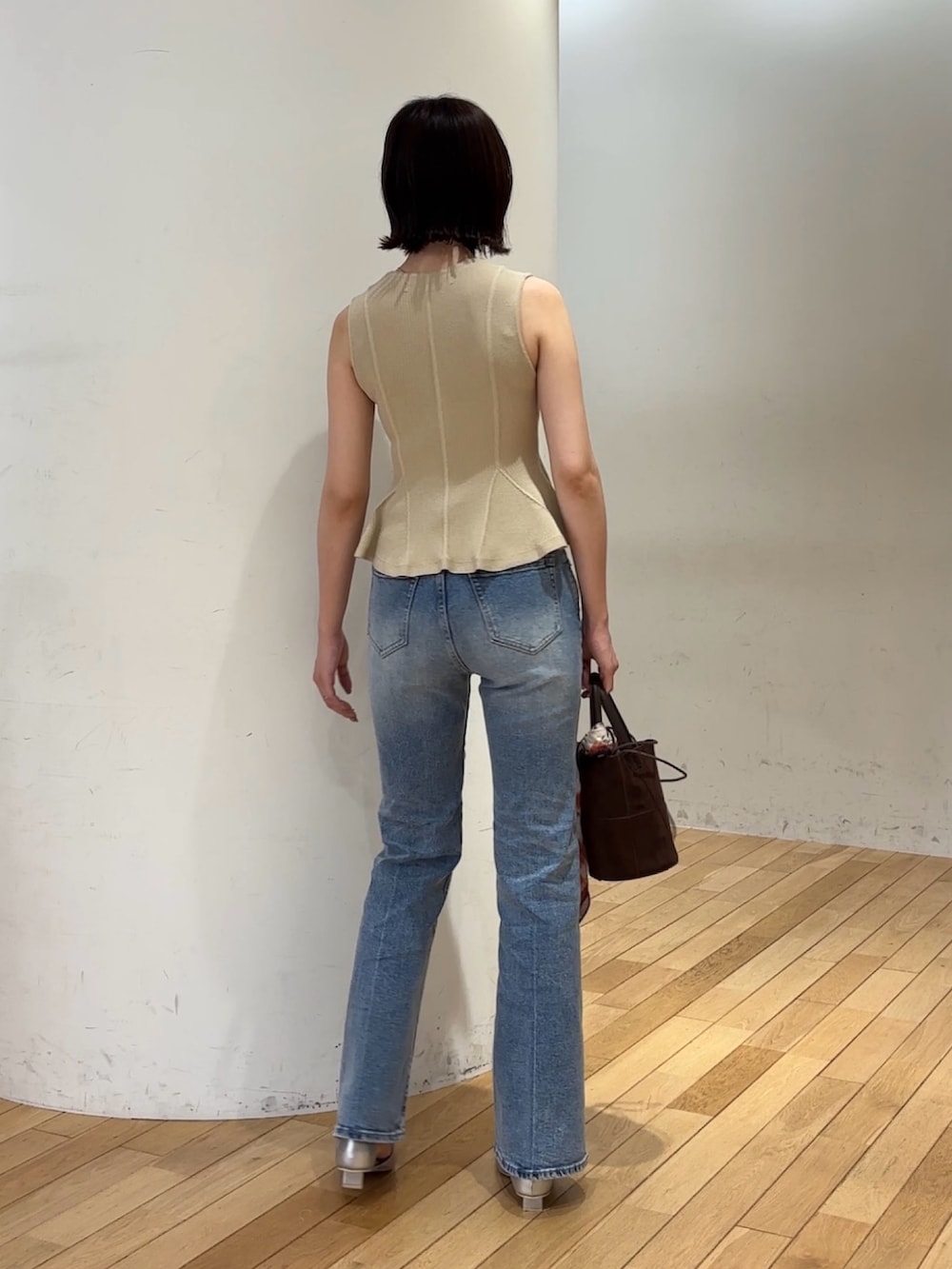 ブルー系のデニムパンツ、ブラウン系のハンドバッグ、シルバー系のパンプスを着用したレディースの夏コーディネートの3枚目の写真