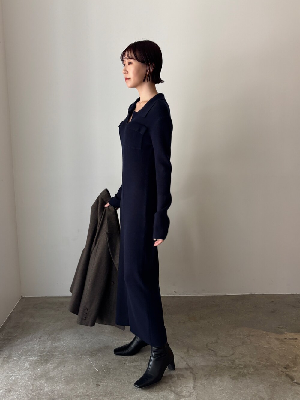 ブルー系のワンピース、ブラウン系のテーラードジャケット、ブラック系のブーツを着用したレディースの秋コーディネートの2枚目の写真