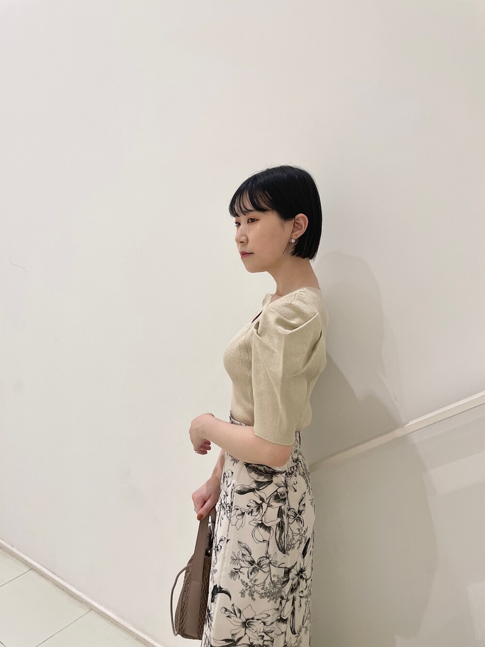 ホワイト系のスカート、ベージュ系のニット/セーター、ブラウン系のハンドバッグを着用したレディースの春コーディネートの6枚目の写真