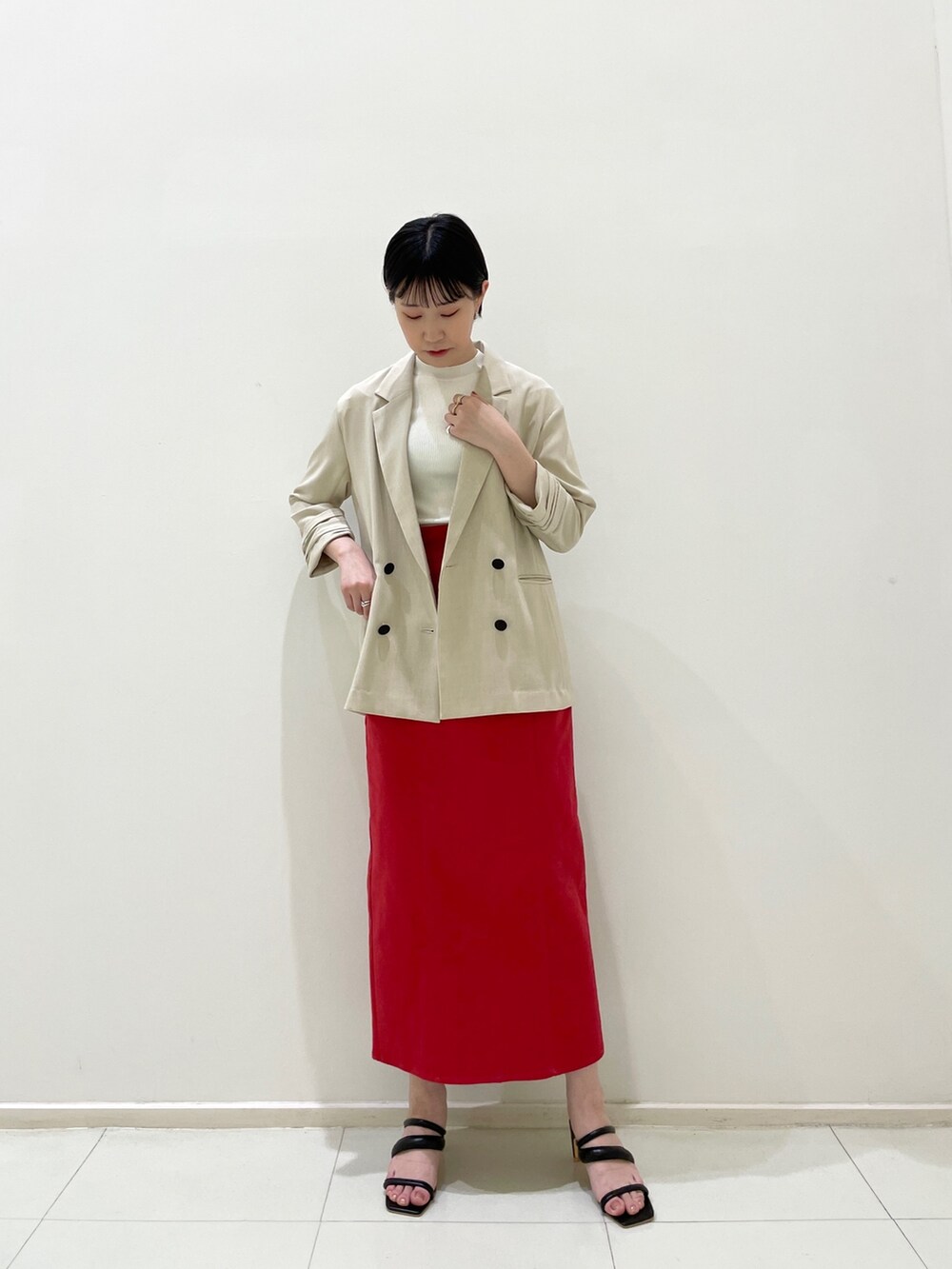 レッド系のスカート、ブラック系のサンダル、ベージュ系のテーラードジャケットを着用したレディースの春コーディネートの3枚目の写真