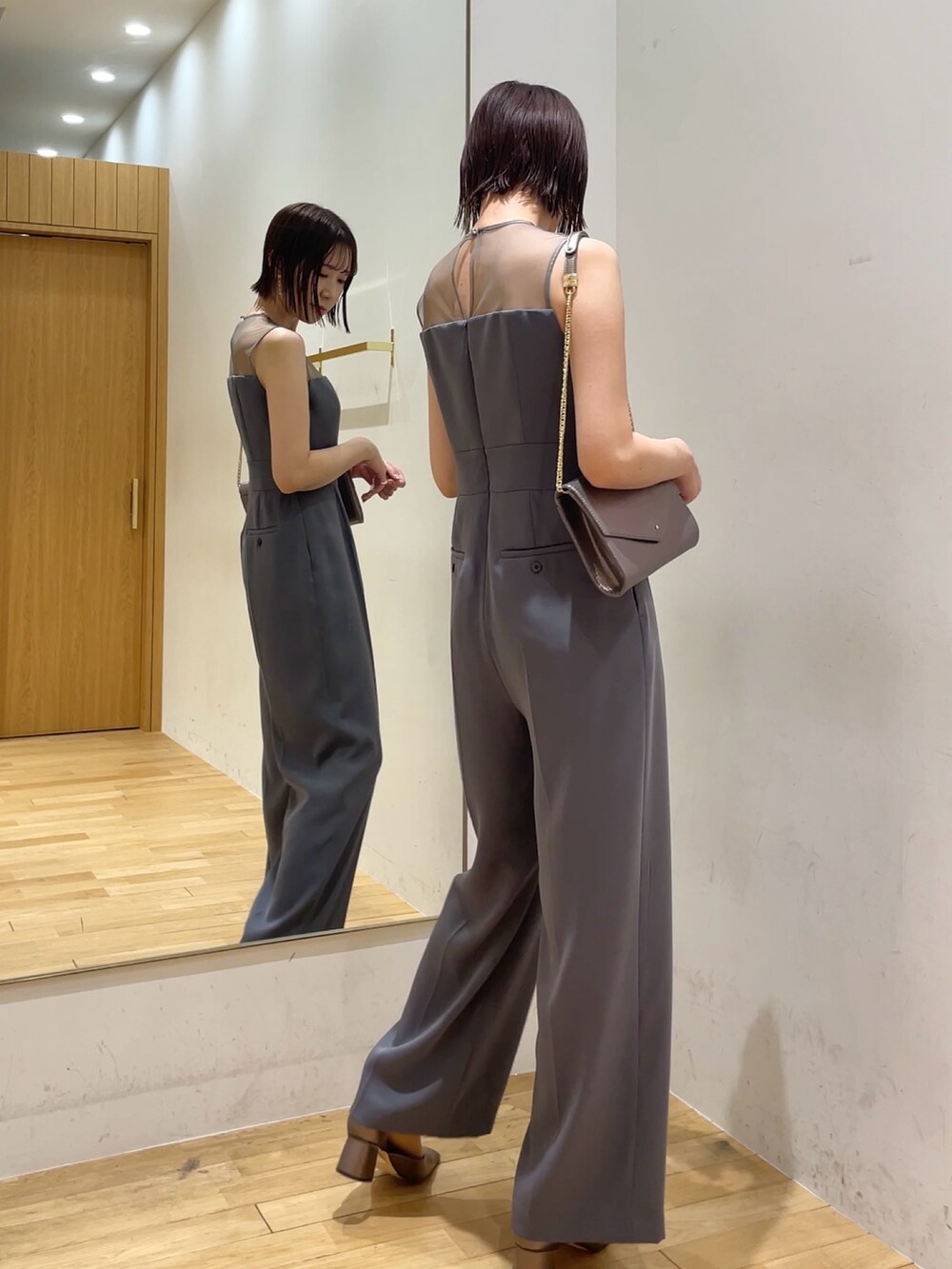 シルバー系のハンドバッグ、その他のパンプス、グレー系のパンツドレスを着用したレディースの冬コーディネートの6枚目の写真