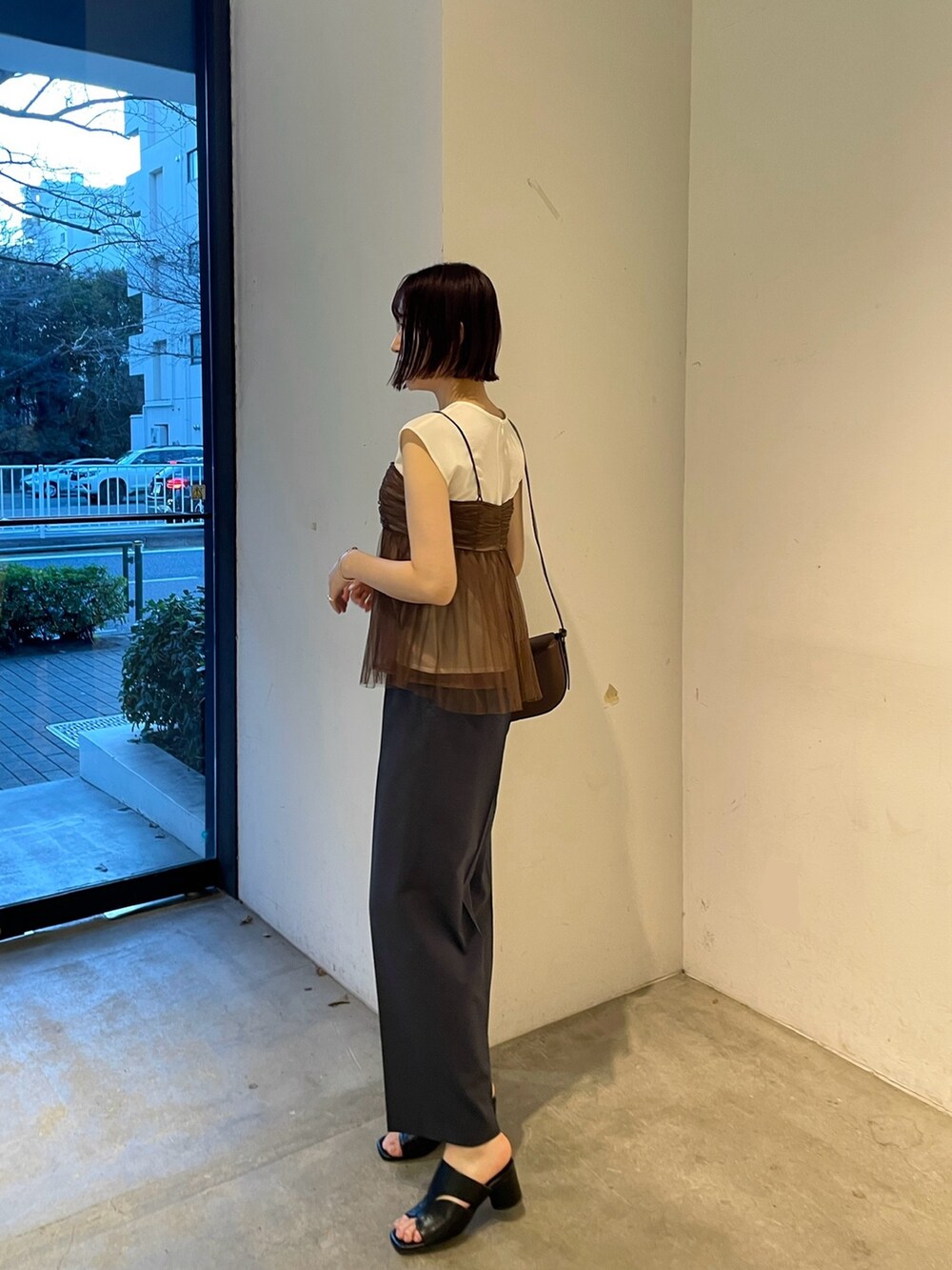 ブラウン系のTシャツ/カットソー、ブルー系のスラックス、ブラック系のサンダルを着用したレディースの春コーディネートの3枚目の写真