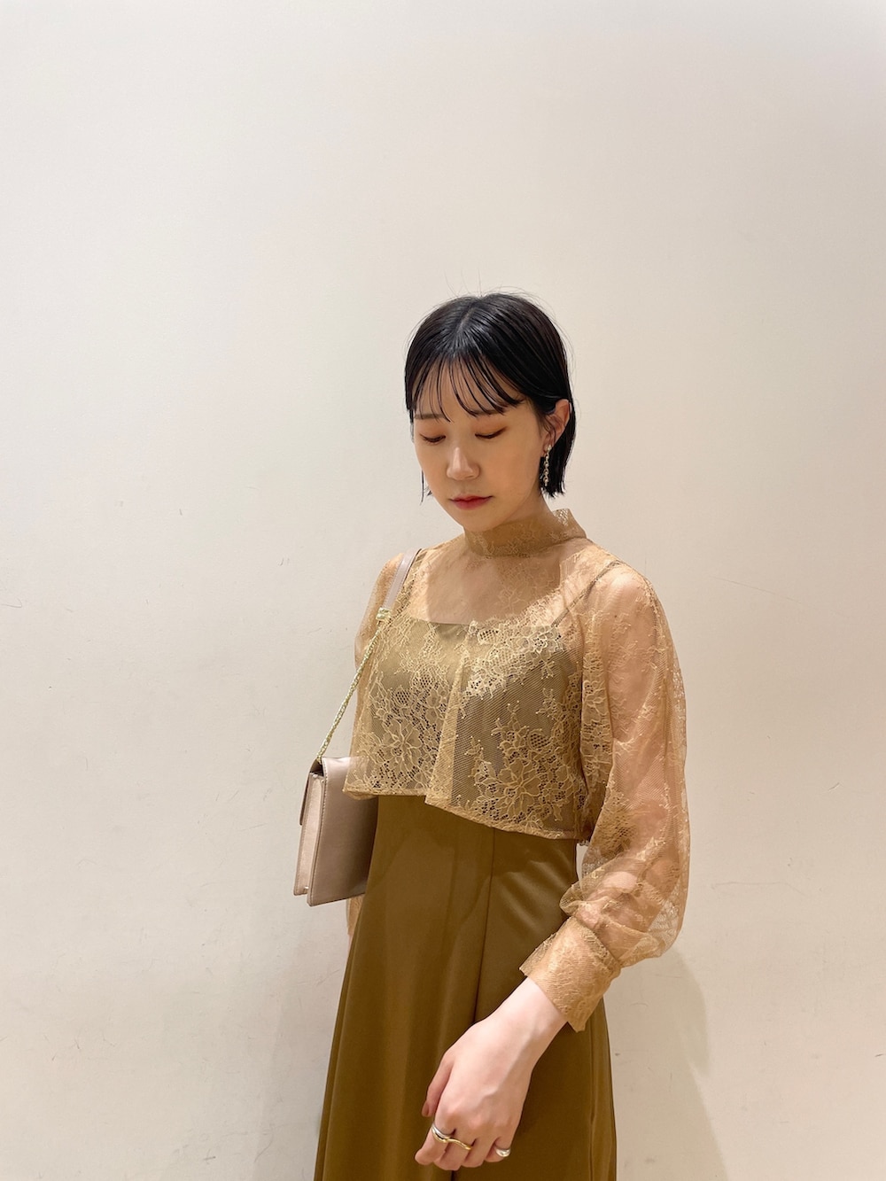 ブラウン系のドレス、ベージュ系のクラッチバッグ、ベージュ系のパンプスを着用したレディースの夏コーディネートの6枚目の写真