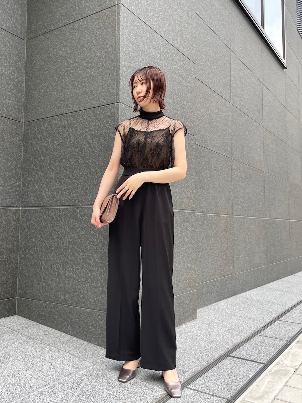 その他のパンプス、ゴールド系のクラッチバッグ、ブラック系のパンツドレスを着用したレディースの春コーディネートの2枚目の写真