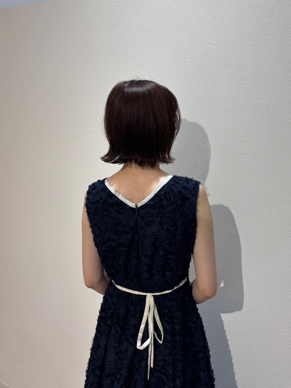 ブルー系のワンピース、ブラウン系のハンドバッグ、ホワイト系のサンダルを着用したレディースの夏コーディネートの5枚目の写真